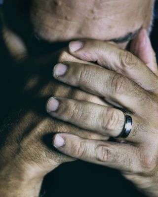 man with his hands covering his face looking upset