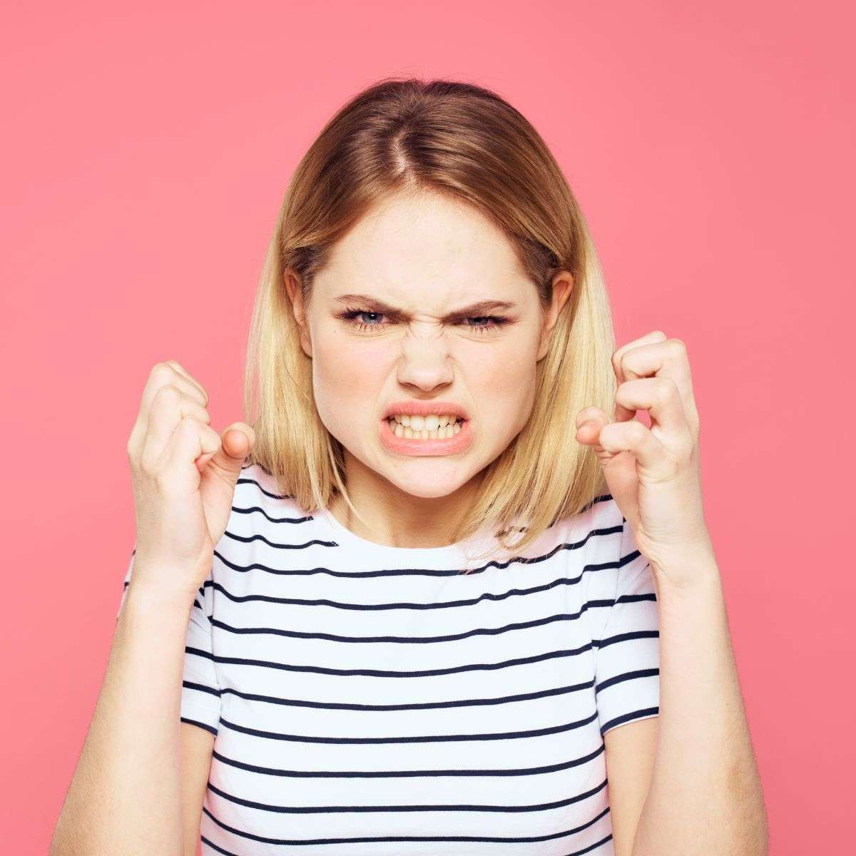 Mindful Healing Anger Management Treatment in New Jersey angry blonde woman in a striped t-shirt and a pink background