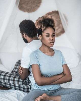 man and woman with their backs to each other with her facing the camera and looking angry