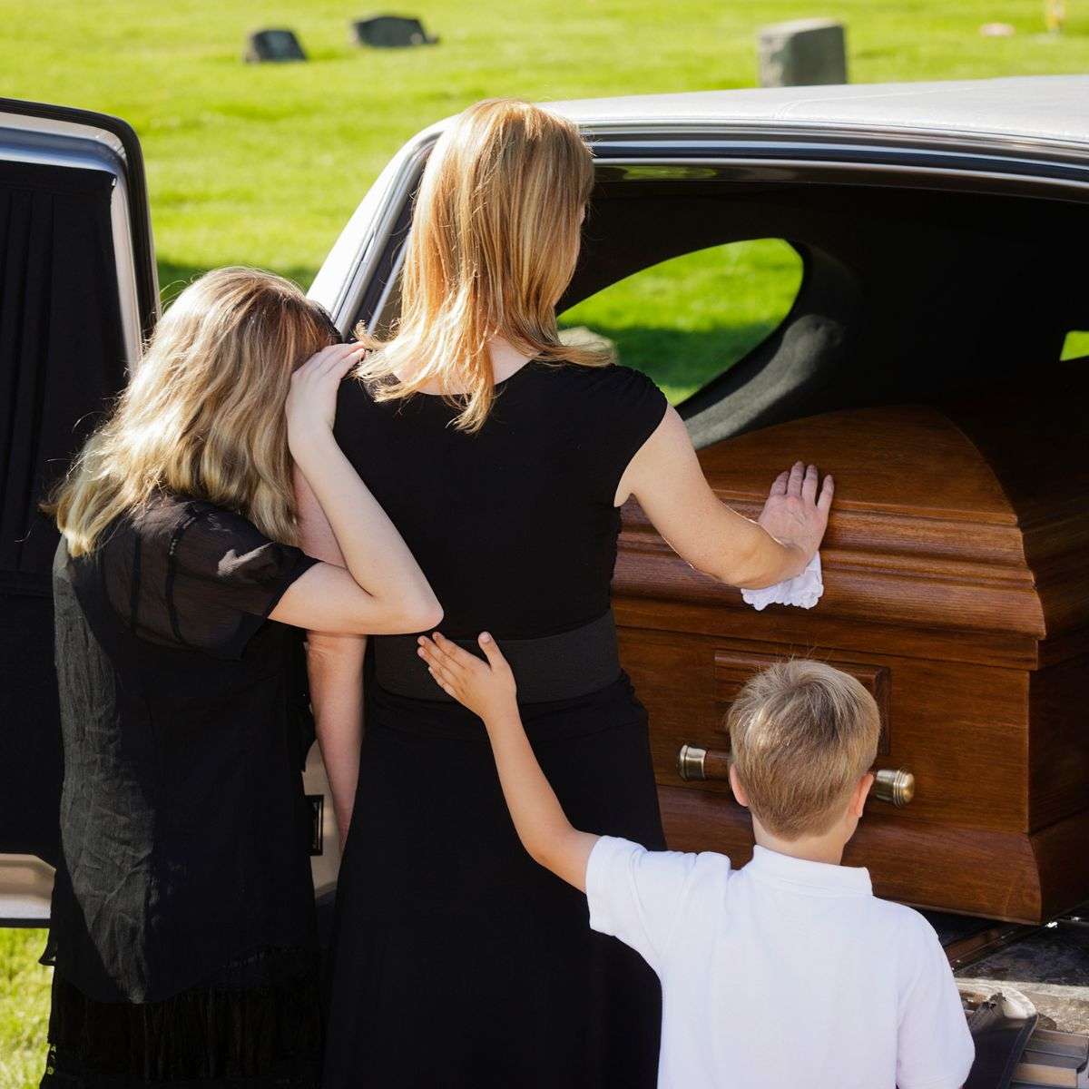 Mindful Healing Grief Counseling in New Jersey woman with two children standing at a casket in the back of a hearse
