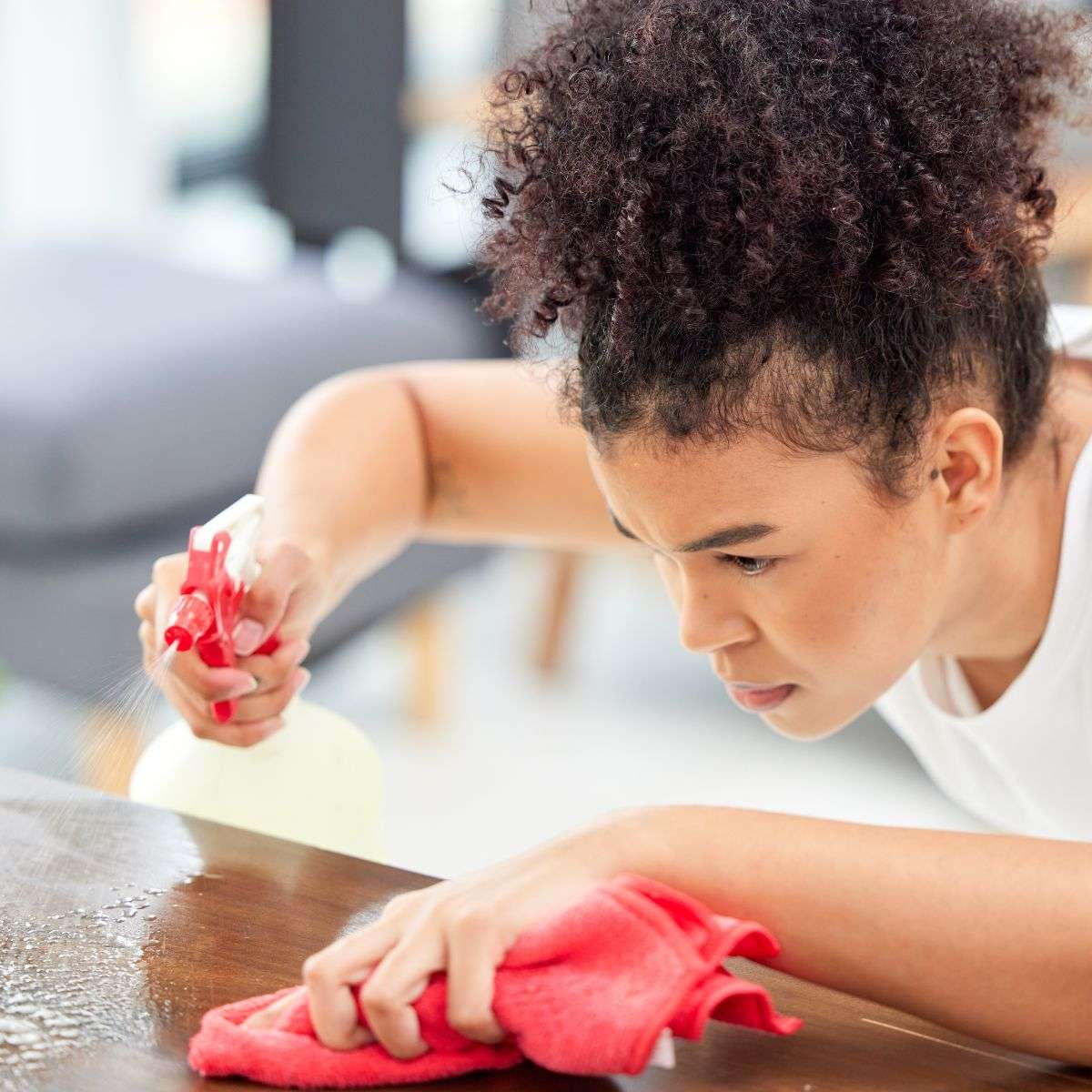 Mindful Healing OCD Treatment in New Jersey woman with a pony tail, spraying and cleaning off a table obsessively