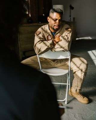 Mindful Healing PTSD Therapy in New Jersey sad male soldier looking down at the floor while talking to a therapist