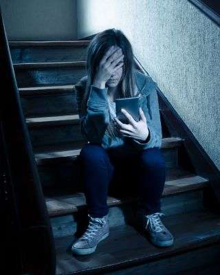 young woman sitting on the stairs looking at her phone