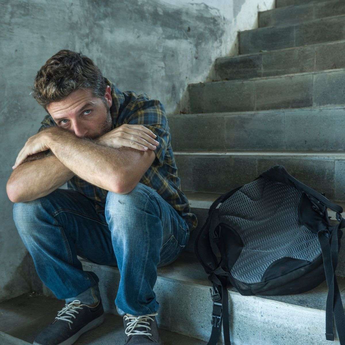 Mindful Healing Sexual abuse Treatment in New Jersey high school aged boy on steps next to his backback, his face covered by his arms and looking scared