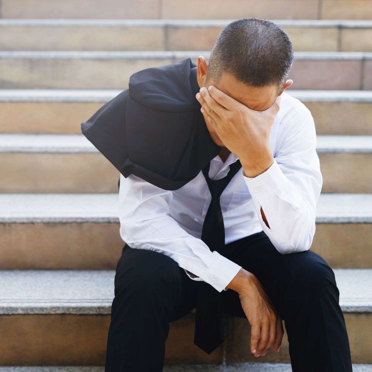 Mindful Healing Stress Disorder Treatment in New Jersey man sitting outside on concrete steps in a business suit, with his head down looking very stressed out