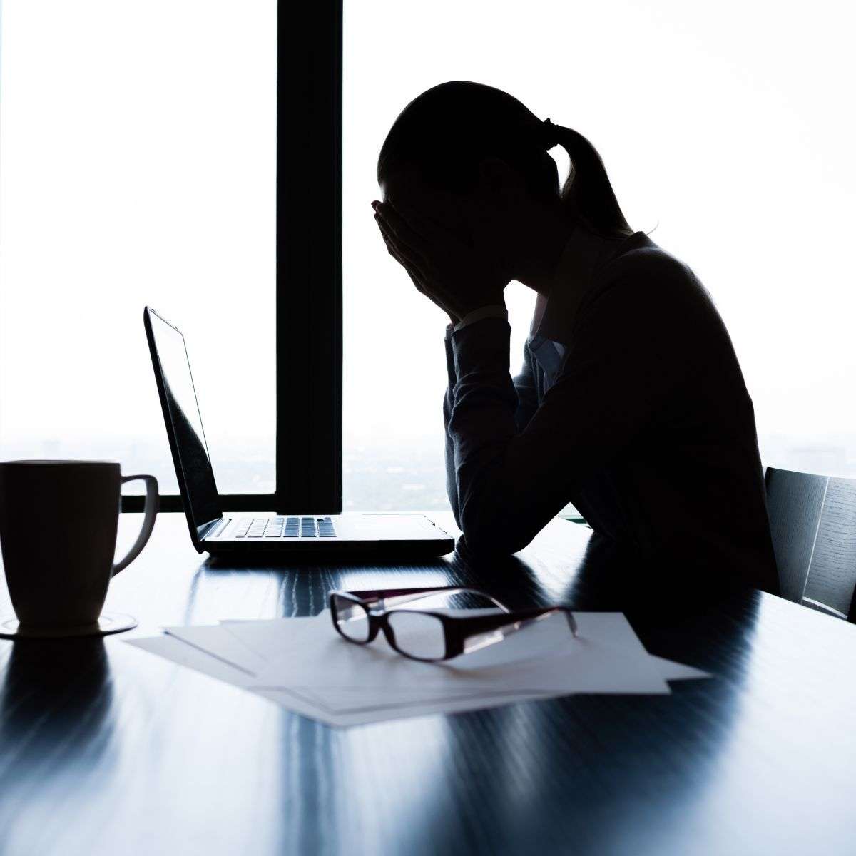 Mindful Healing Stress Disorder Treatment in New Jersey woman in a corporate office sitting at the table in front of her computer with her head down, obviously stressed out