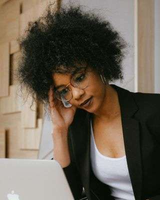 woman sitting in front of a computer looking overwhelmed and stressed out