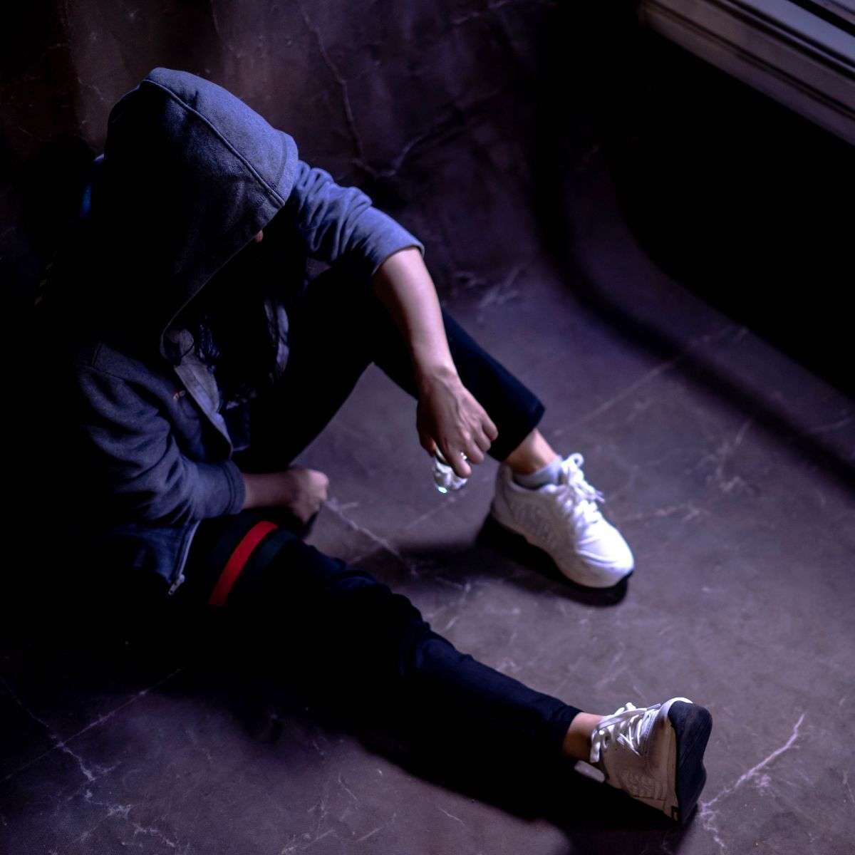 Mindful Healing Substance Use Treatment in New Jersey young man sitting on the ground with a hoodie covering his head, hiding something