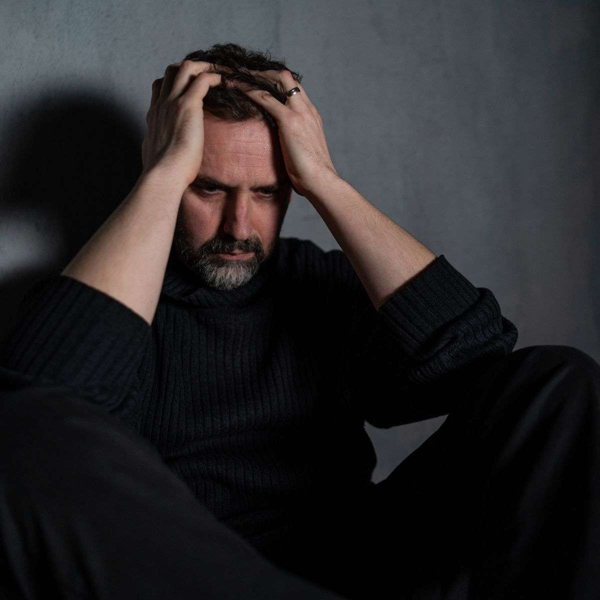 Mindful Healing Psychiatric Evaluation Man sitting against a wall with his head in his hands