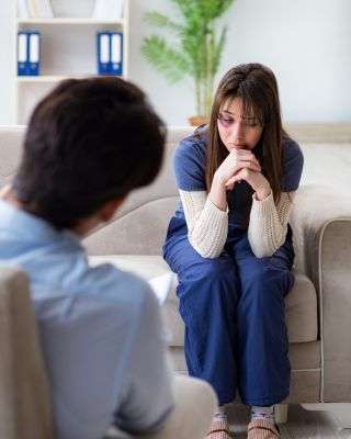 Mindful Healing Trauma Treatment in New Jersey young woman with a black eye sitting on a couch talking to a therapist